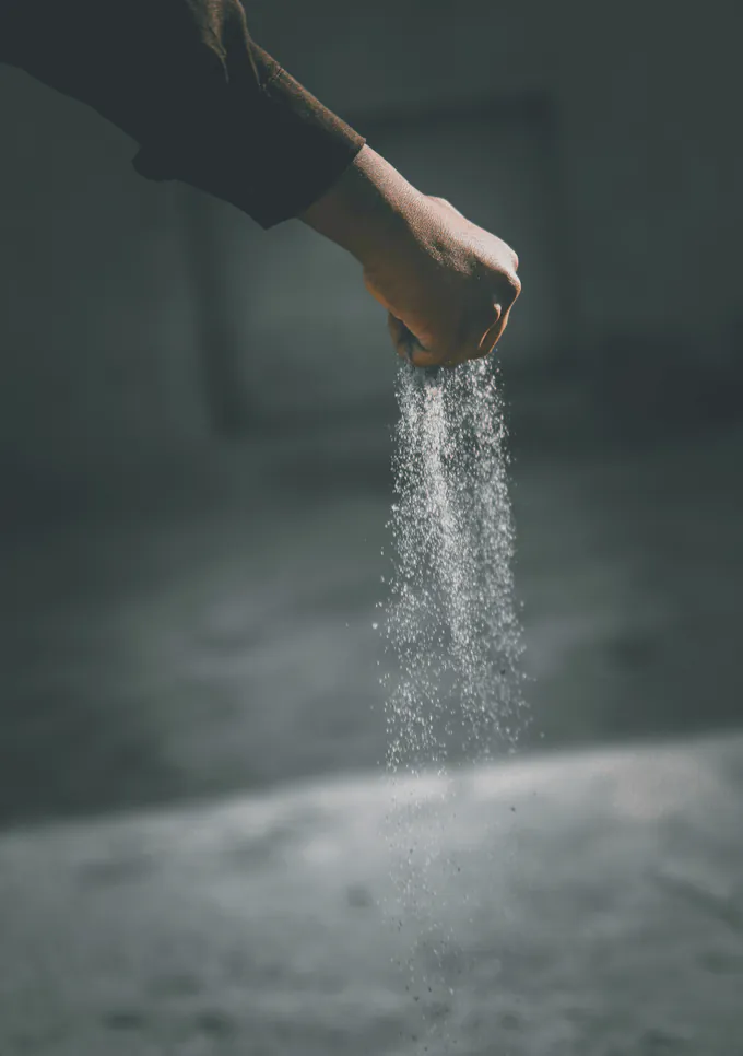 Flour falling from a hand in low light