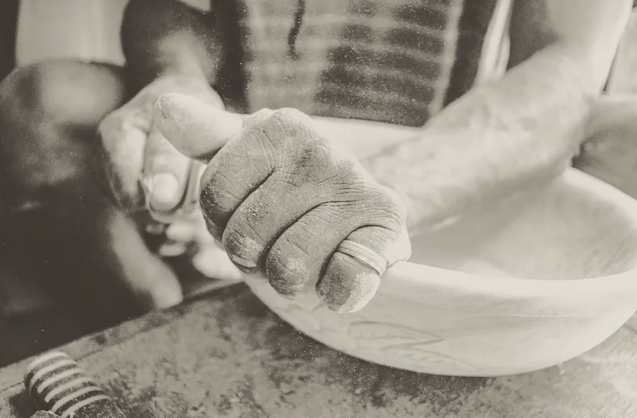 Floured hands working dough in a bowl