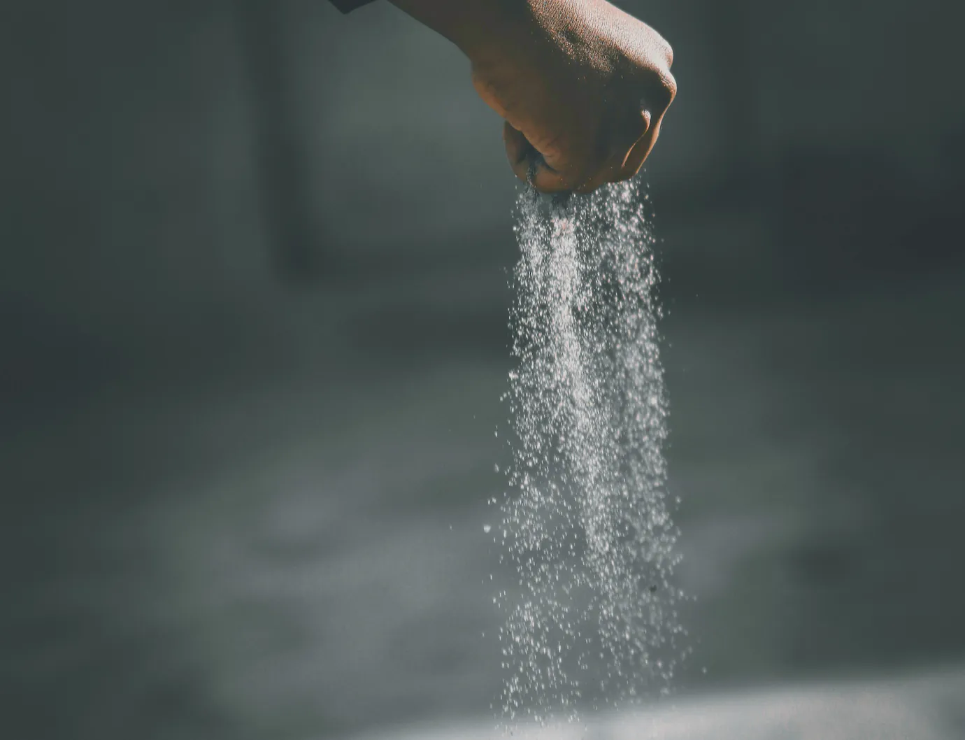 Flour falling from a hand in low light